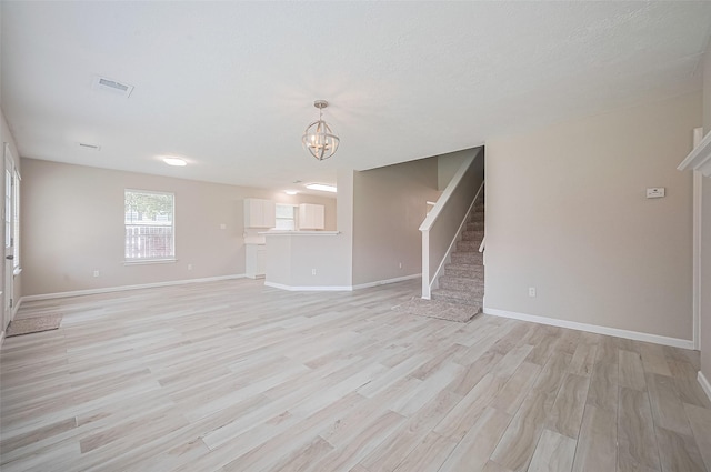 16502 N Glade Dr, Houston, TX 77073 - unfurnished living room with a chandelier, stairway, light wood finished floors, and baseboards