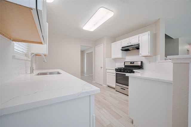 16502 N Glade Dr, Houston, TX 77073 - kitchen with stainless steel range with gas stovetop, a sink, under cabinet range hood, decorative backsplash, and white cabinets