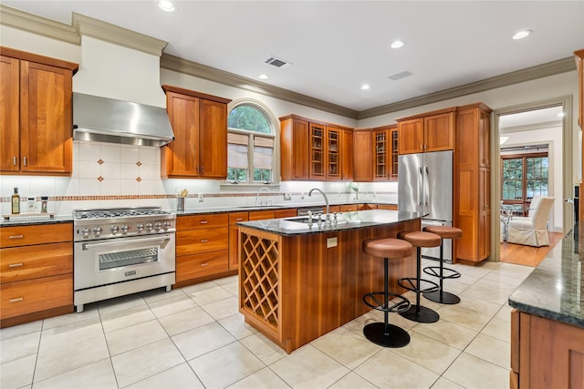 3502 Underwood St, Houston, TX 77025 - kitchen featuring stainless steel appliances, wall chimney exhaust hood, ornamental molding, healthy amount of natural light, and brown cabinets