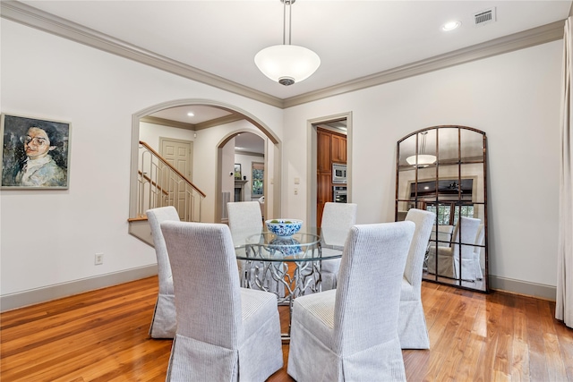 3502 Underwood St, Houston, TX 77025 - dining room with arched walkways, crown molding, light wood-style flooring, and stairs
