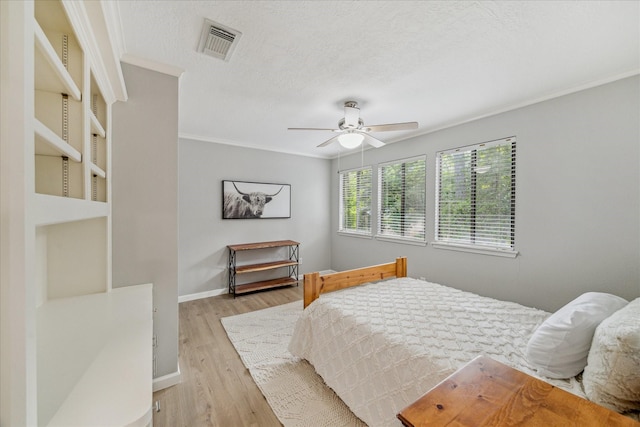 2411 Oakbank Dr, Houston, TX 77339 - bedroom featuring crown molding, light wood-type flooring, baseboards, a ceiling fan, and a textured ceiling