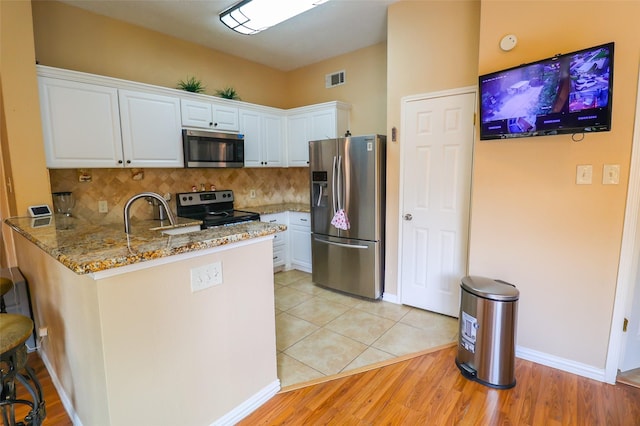 13555 Portobello Dr, Houston, TX 77083 - kitchen featuring appliances with stainless steel finishes, a peninsula, white cabinetry, light stone countertops, and a sink