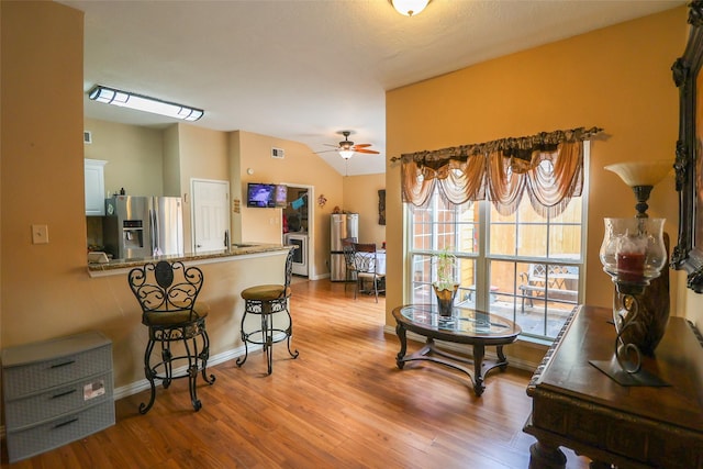 13555 Portobello Dr, Houston, TX 77083 - kitchen with stainless steel fridge, wood finished floors, a ceiling fan, a breakfast bar area, and lofted ceiling