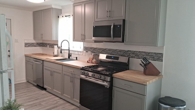 402 Spruce Lake Rd, Houston, TX 77336 - kitchen featuring appliances with stainless steel finishes, gray cabinetry, a sink, backsplash, and crown molding