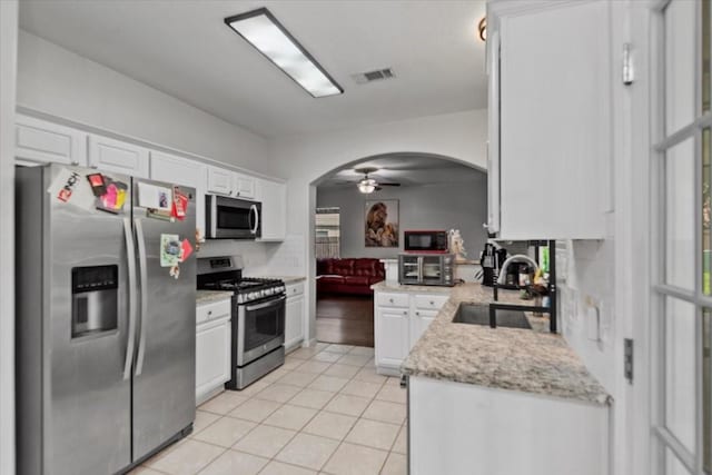 8731 Majesticbrook Dr, Houston, TX 77095 - kitchen with appliances with stainless steel finishes, a sink, arched walkways, white cabinets, and light tile patterned floors