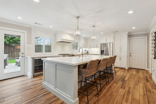 2502 Briarbrook Dr, Houston, TX 77042 - kitchen with wine cooler, custom range hood, stainless steel fridge with ice dispenser, ornamental molding, and light countertops