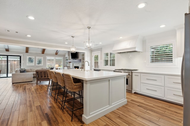 2502 Briarbrook Dr, Houston, TX 77042 - kitchen featuring stainless steel appliances, premium range hood, beamed ceiling, open floor plan, and white cabinets