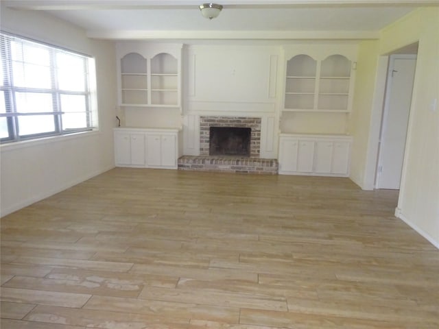 4810 Theall Rd, Houston, TX 77066 - unfurnished living room with light wood-type flooring, a fireplace, baseboards, and built in shelves