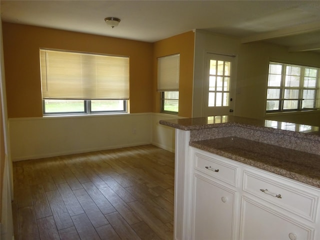 4810 Theall Rd, Houston, TX 77066 - kitchen featuring white cabinetry, wood finished floors, baseboards, and dark stone countertops