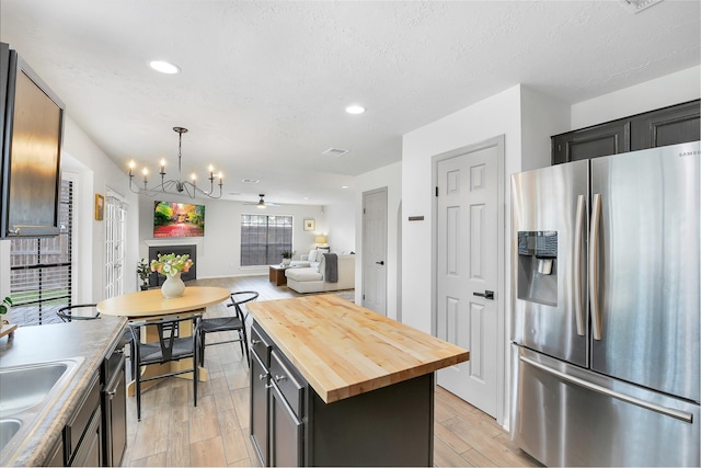 16202 Elm Point Ct, Houston, TX 77095 - kitchen with stainless steel refrigerator with ice dispenser, wooden counters, light wood-style flooring, open floor plan, and a chandelier