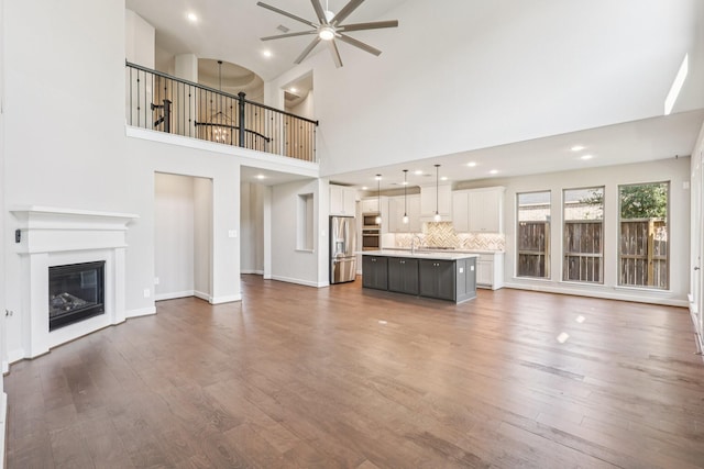 28814 Creekside Bend Dr, Fulshear, TX 77441 - unfurnished living room featuring a ceiling fan, dark wood-style flooring, a glass covered fireplace, recessed lighting, and a sink
