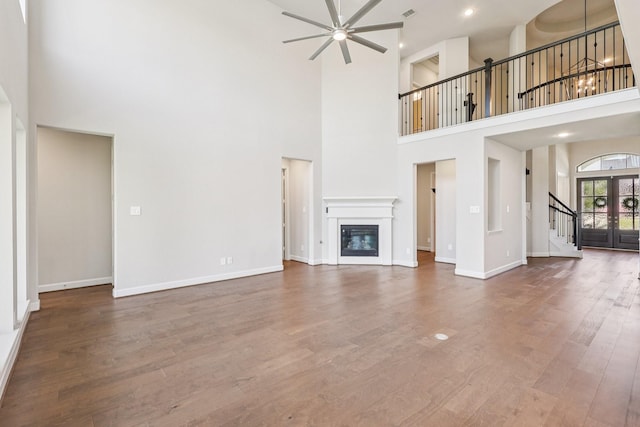 28814 Creekside Bend Dr, Fulshear, TX 77441 - unfurnished living room with stairs, ceiling fan, a towering ceiling, wood finished floors, and baseboards