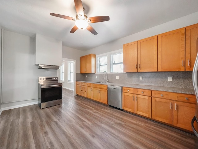 2402 49th St, Galveston, TX 77551 - kitchen featuring appliances with stainless steel finishes, a sink, ceiling fan, wood finished floors, and backsplash