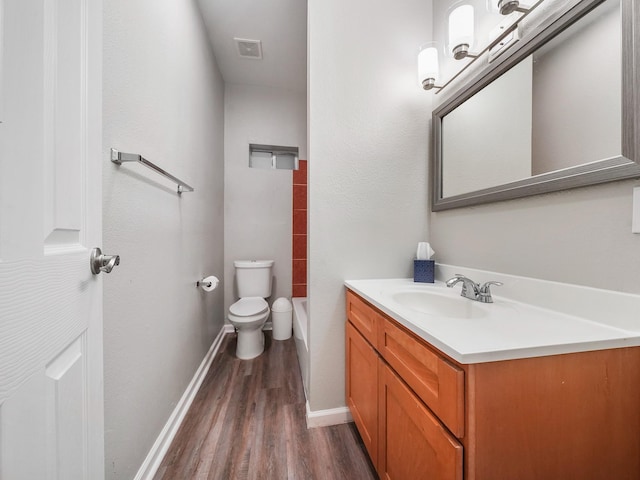 2402 49th St, Galveston, TX 77551 - bathroom featuring vanity, wood finished floors, baseboards, a tub, and toilet