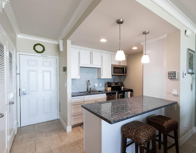 1401 E Beach Dr Unit 903, Galveston, TX 77550 - kitchen with appliances with stainless steel finishes, a kitchen bar, white cabinets, tasteful backsplash, and dark stone counters