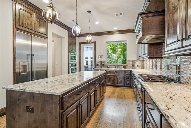 6619 Minola St, Houston, TX 77007 - kitchen featuring built in appliances, light stone counters, a kitchen island, dark brown cabinetry, and crown molding