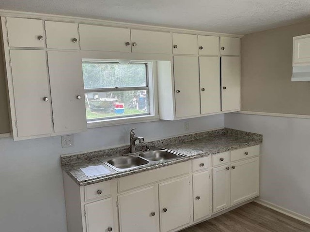 805 E Calhoun St, El Campo, TX 77437 - kitchen with a sink, white cabinets, wood finished floors, a textured ceiling, and baseboards