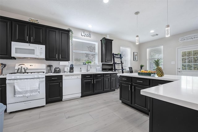 9303 Filaree Ridge Ln, Houston, TX 77089 - kitchen featuring white appliances, dark cabinetry, light countertops, a sink, and recessed lighting