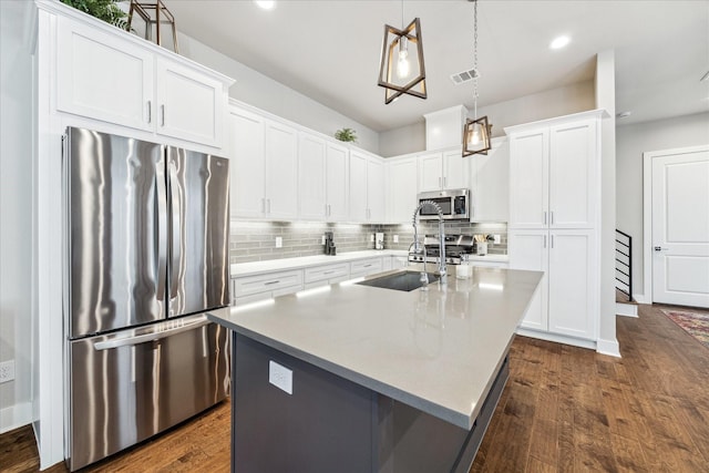 823 Mansfield St Unit E, Houston, TX 77091 - kitchen with appliances with stainless steel finishes, dark wood-style floors, an island with sink, backsplash, and white cabinets