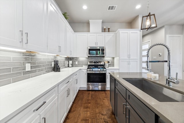 823 Mansfield St Unit E, Houston, TX 77091 - kitchen featuring stainless steel appliances, a sink, white cabinets, light stone counters, and backsplash