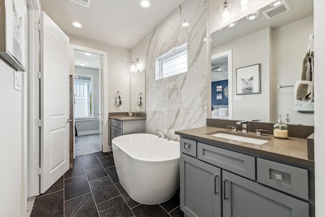 823 Mansfield St Unit E, Houston, TX 77091 - ensuite bathroom featuring a soaking tub, two vanities, healthy amount of natural light, marble look tile flooring, and recessed lighting