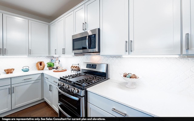 23514 Malbec Dr, Alvin, TX 77511 - kitchen featuring appliances with stainless steel finishes, light countertops, tasteful backsplash, white cabinetry, and dark wood-style flooring