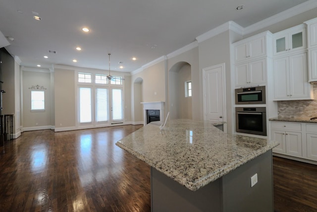 9642 Fannin Sta W, Houston, TX 77045 - kitchen featuring stainless steel oven, white cabinets, crown molding, tasteful backsplash, and a high end fireplace
