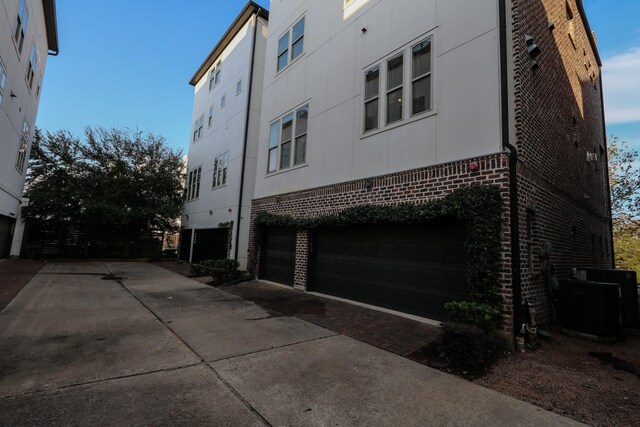 9642 Fannin Sta W, Houston, TX 77045 - view of side of home with brick siding, an attached garage, central air condition unit, driveway, and stucco siding