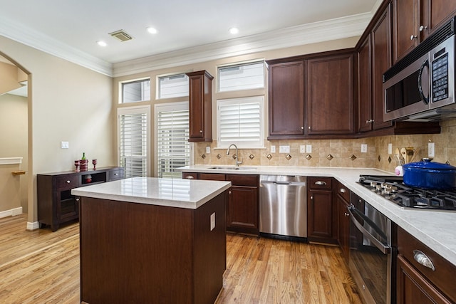 641 Hartman St, Houston, TX 77007 - kitchen featuring stainless steel appliances, a sink, light wood finished floors, arched walkways, and a kitchen island