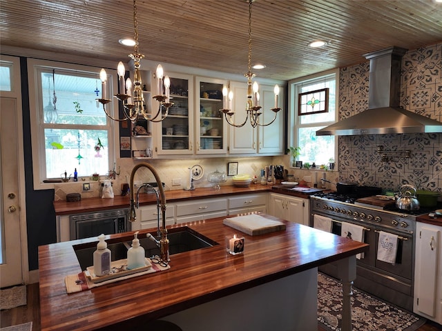 1017 Water St, Navasota, TX 77868 - kitchen with wood counters, wall chimney range hood, double oven range, a chandelier, and glass insert cabinets