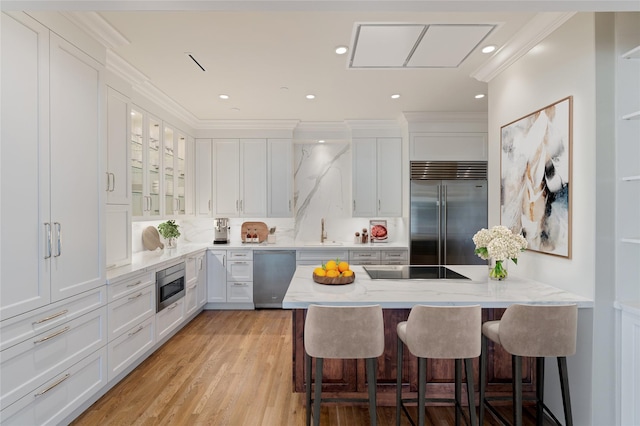 511 S Post Oak Ln Unit 2B, Houston, TX 77056 - kitchen with built in appliances, a breakfast bar area, white cabinets, light stone countertops, and crown molding