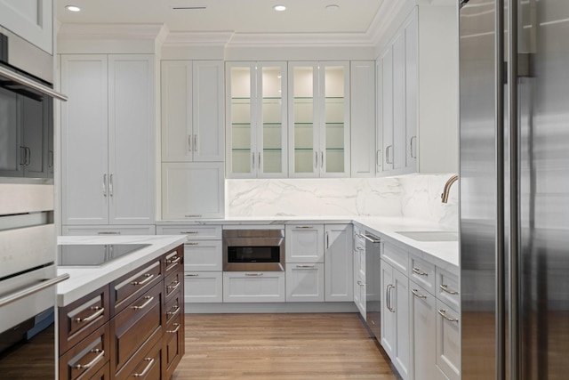 511 S Post Oak Ln Unit 2B, Houston, TX 77056 - kitchen featuring appliances with stainless steel finishes, a sink, white cabinetry, dark brown cabinetry, and light wood-style flooring