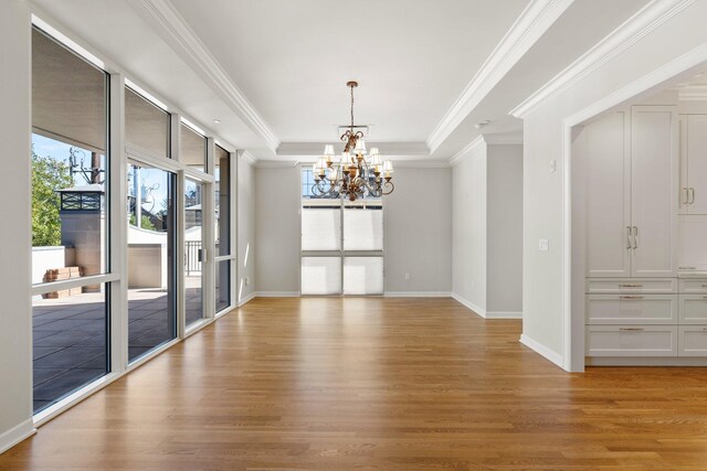 511 S Post Oak Ln Unit 2B, Houston, TX 77056 - spare room featuring a chandelier, light wood-style floors, a raised ceiling, ornamental molding, and baseboards