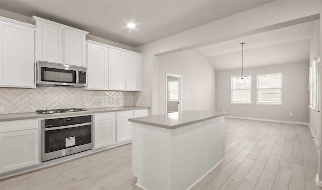 32407 Tallow Creek Dr, Waller, TX 77484 - kitchen with appliances with stainless steel finishes, tasteful backsplash, light wood-style floors, white cabinetry, and lofted ceiling