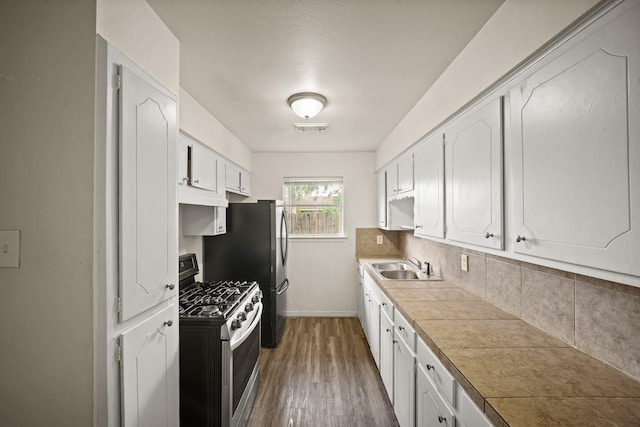 231 Gruss Dr, Houston, TX 77060 - kitchen with gas range, a sink, tasteful backsplash, under cabinet range hood, and dark wood finished floors
