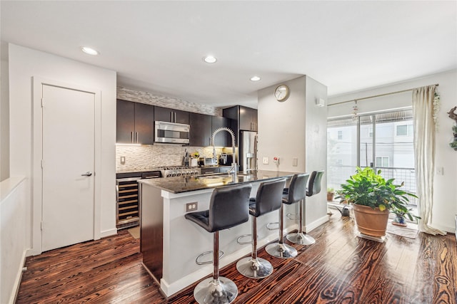 429 Meadow St, Houston, TX 77020 - kitchen featuring appliances with stainless steel finishes, dark wood finished floors, a breakfast bar, backsplash, and wine cooler