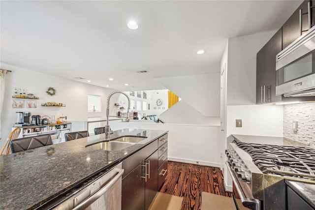 429 Meadow St, Houston, TX 77020 - kitchen featuring stainless steel appliances, dark wood-style floors, dark stone countertops, decorative backsplash, and a sink