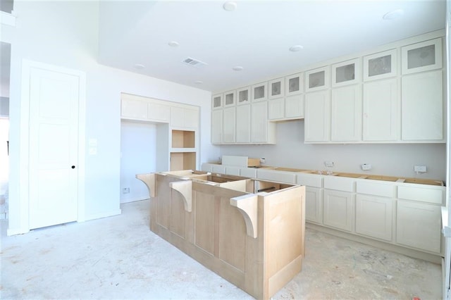 2296 Vargas St, Magnolia, TX 77316 - kitchen featuring a center island, glass insert cabinets, and unfinished concrete floors