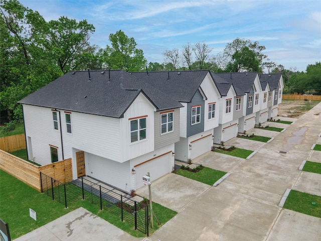 1852 W Tidwell Rd, Houston, TX 77091 - rear view of house featuring board and batten siding, concrete driveway, an attached garage, and a shingled roof