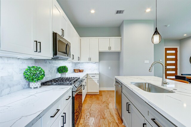1830 W Tidwell Rd, Houston, TX 77091 - kitchen with stainless steel appliances, light wood-style flooring, pendant lighting, light stone counters, and tasteful backsplash