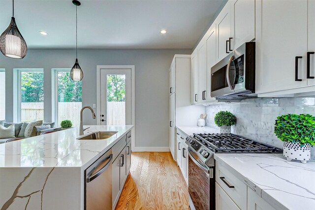 1830 W Tidwell Rd, Houston, TX 77091 - kitchen featuring appliances with stainless steel finishes, light wood-type flooring, tasteful backsplash, light stone counters, and hanging light fixtures