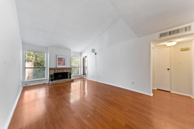 10053 Westpark Dr Unit 332, Houston, TX 77042 - unfurnished living room with wood finished floors, vaulted ceiling, a fireplace with raised hearth, and baseboards