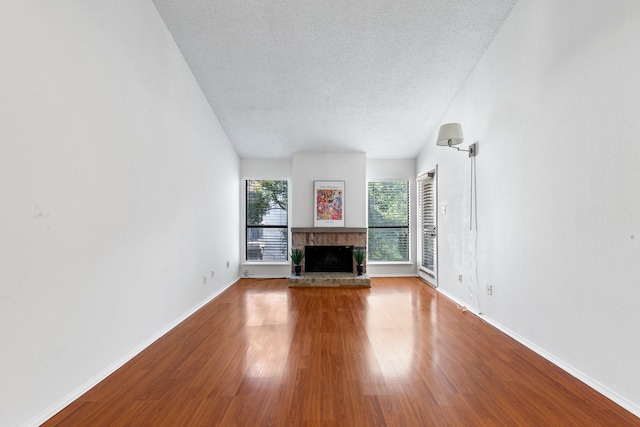 10053 Westpark Dr Unit 332, Houston, TX 77042 - unfurnished living room featuring a fireplace with raised hearth, a textured ceiling, baseboards, and wood finished floors