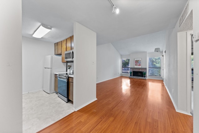 10053 Westpark Dr Unit 332, Houston, TX 77042 - kitchen featuring stainless steel appliances, a fireplace with raised hearth, light wood-style floors, brown cabinets, and light countertops