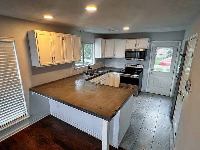 239 Cove Vw, Trinity, TX 75862 - kitchen with appliances with stainless steel finishes, a sink, dark countertops, a peninsula, and white cabinets