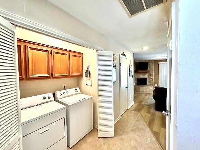 3823 Knollcrest Dr, Montgomery, TX 77356 - laundry room featuring cabinet space, independent washer and dryer, a fireplace, light tile patterned floors, and a heating unit