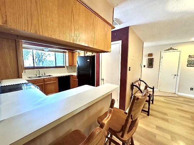 3823 Knollcrest Dr, Montgomery, TX 77356 - kitchen featuring freestanding refrigerator, a textured ceiling, a sink, light countertops, and light wood-style floors