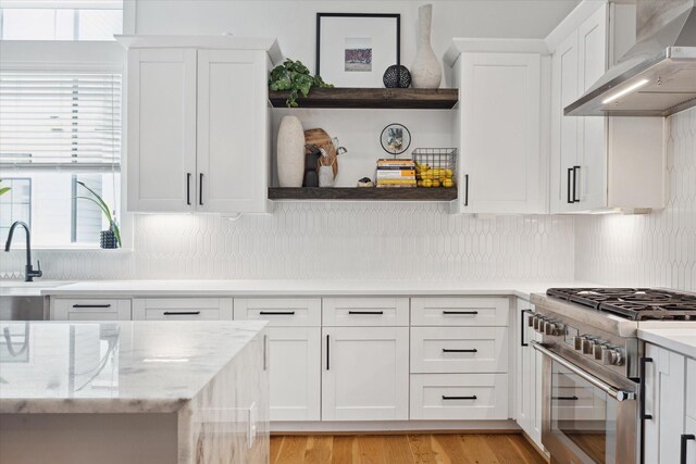 1402 Missouri Unit B, Houston, TX 77006 - kitchen with wall chimney exhaust hood, high end stainless steel range oven, white cabinets, open shelves, and tasteful backsplash