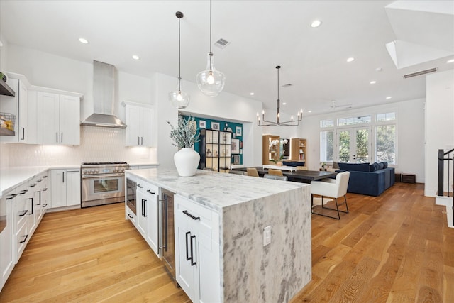 1402 Missouri Unit B, Houston, TX 77006 - kitchen with appliances with stainless steel finishes, wall chimney range hood, a kitchen island, decorative backsplash, and white cabinets