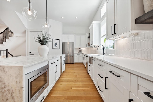 1402 Missouri Unit B, Houston, TX 77006 - kitchen with stainless steel appliances, light wood finished floors, decorative light fixtures, white cabinetry, and recessed lighting
